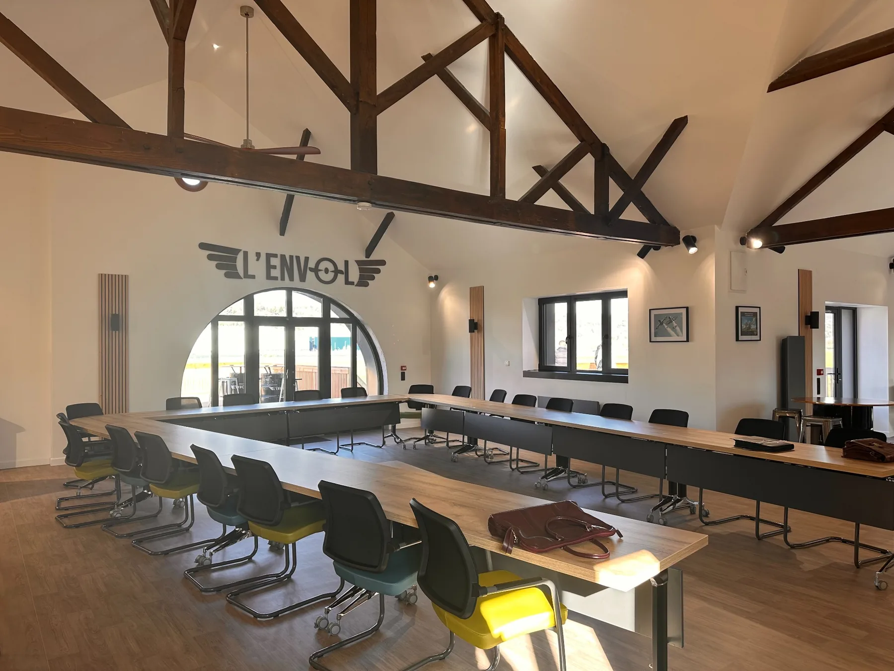 Salle principale L'Envol avec charpente apparente et tables de réunion